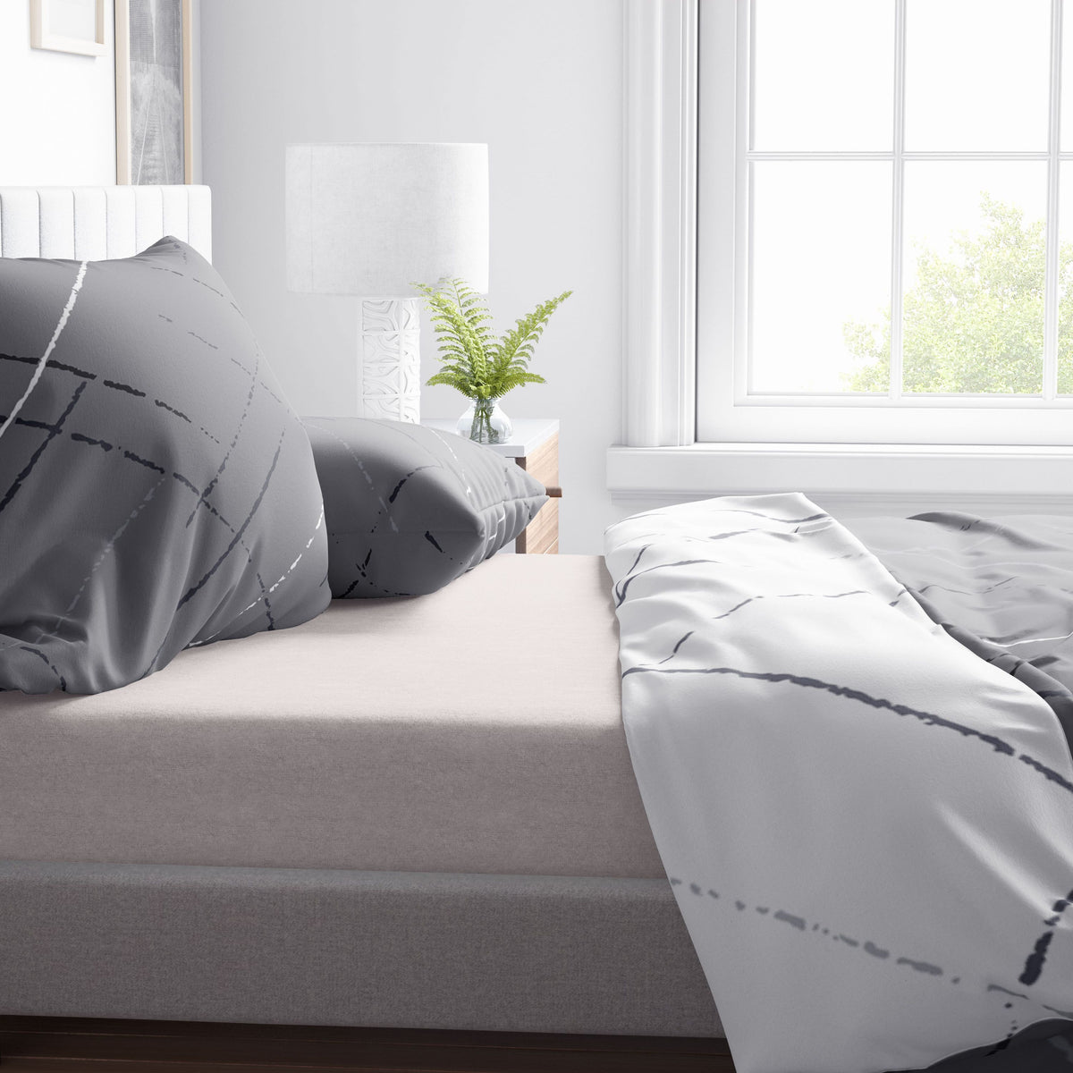 Nahaufnahme der grau-weißen Wendebettwäsche aus Baumwollmischung mit modernem Linienmuster auf einem Bett mit heller Matratze und Tageslicht am Fenster